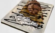 Crepa en plato con helado de chocolate, chantilly y sirope.